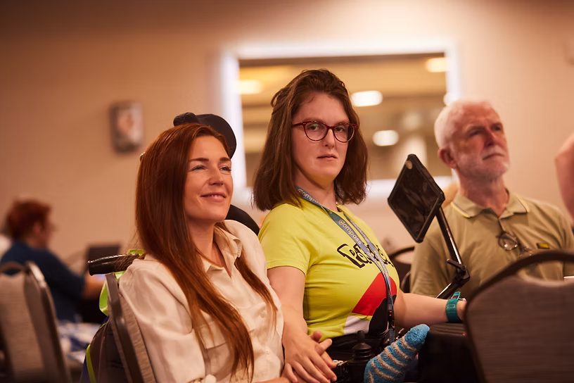 Kathleen Morton (center), who has HNRNPK-NDD or Au-Kline, her sister (left), and father (right) engaged in 2024 foundation conference